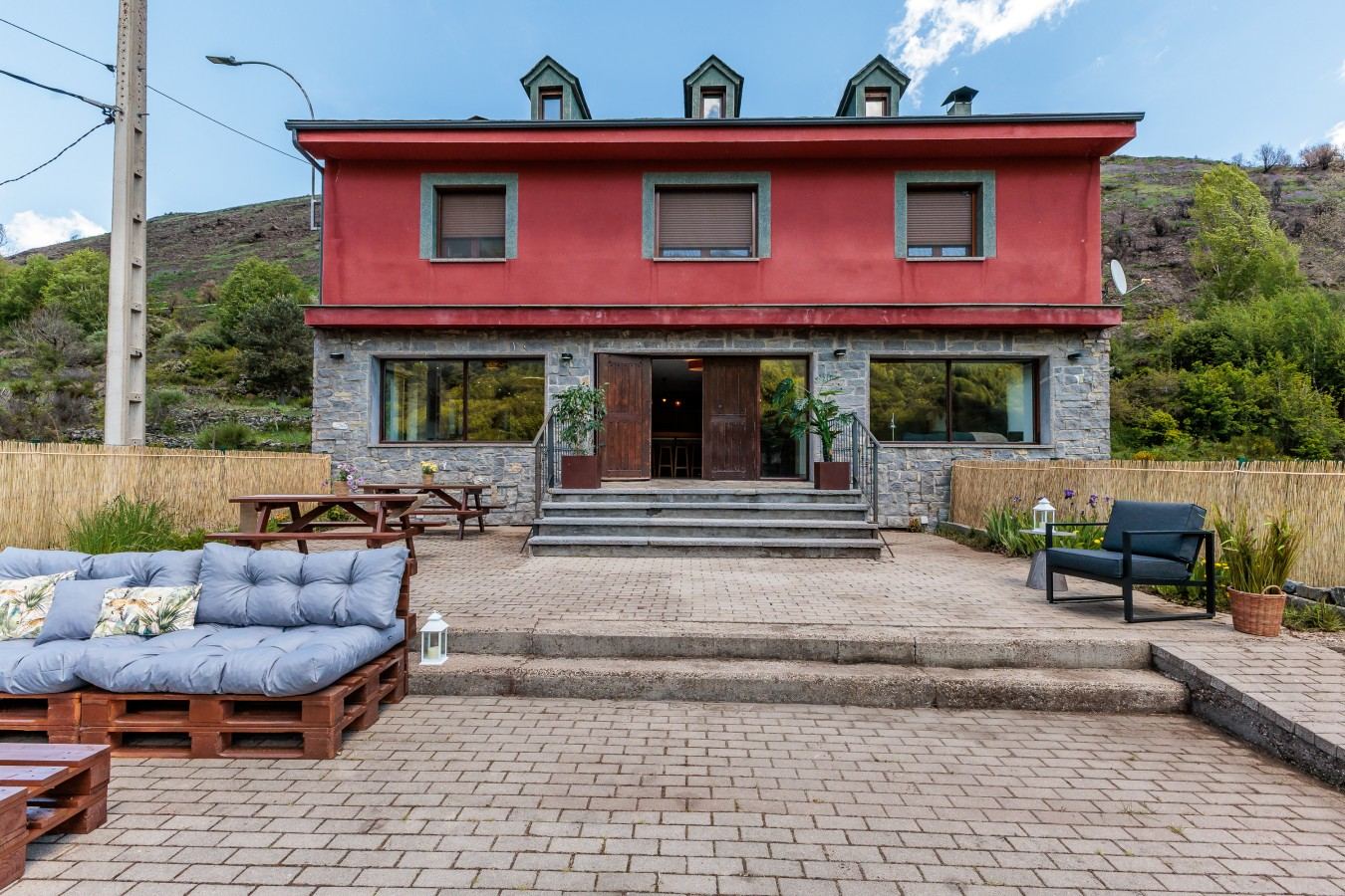 La Casona de Omaña, casa de fachada roja con el monte detrás