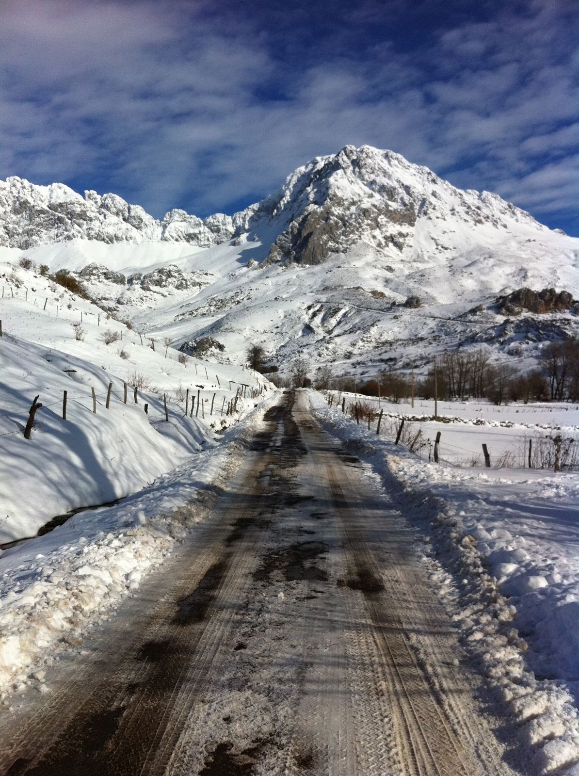 Carretera entre muros de nieve con un pico nevado al fondo