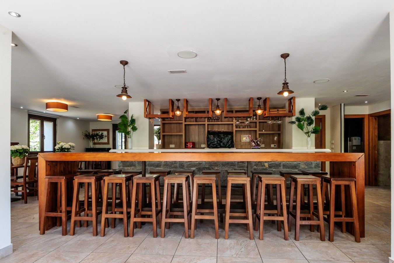 Salón de abajo con barra de bar de madera y piedra y taburetes